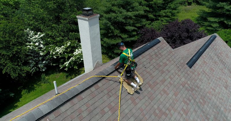 Harnessed Roofer installing shingles