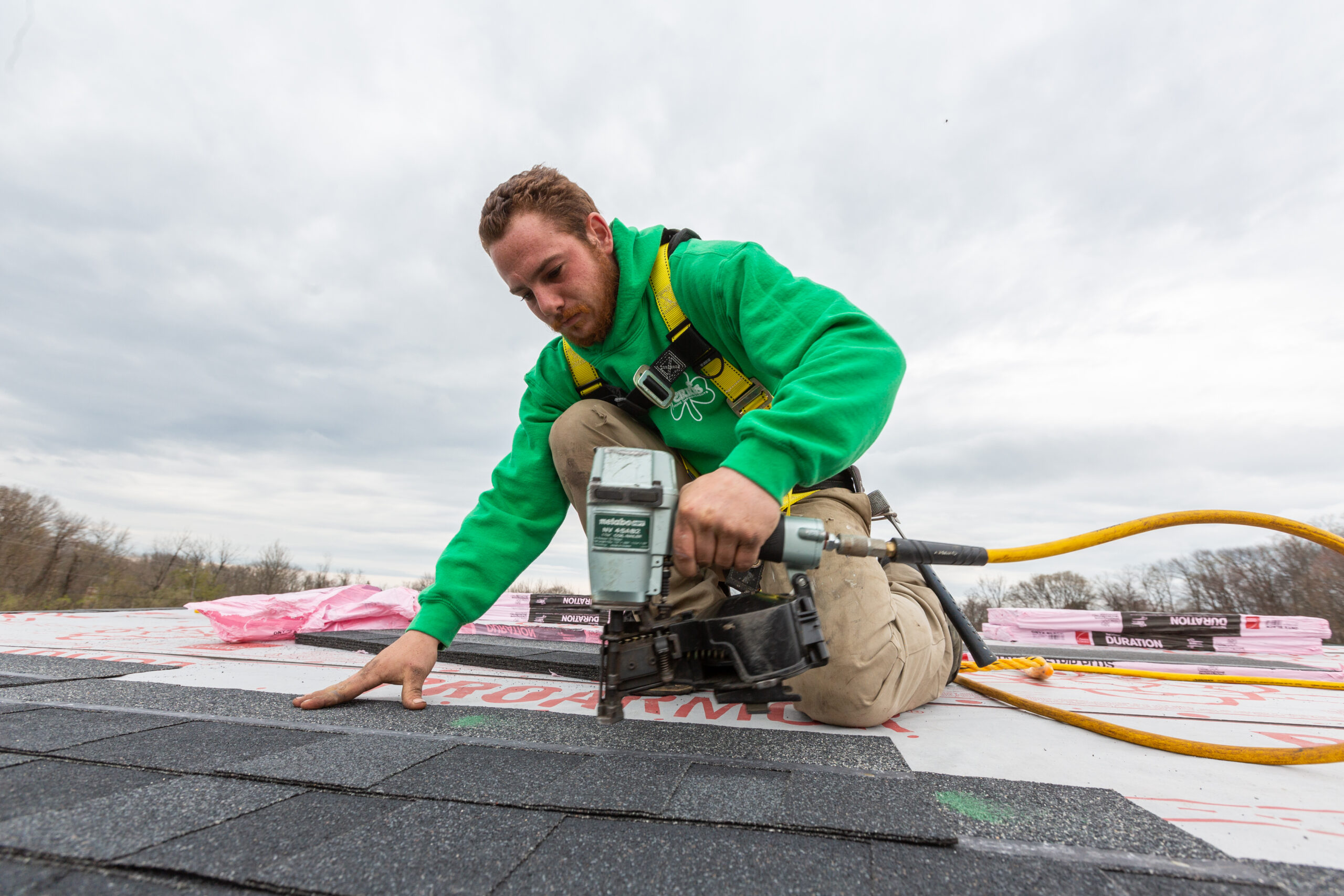 Roofer nailing down shingles on roof